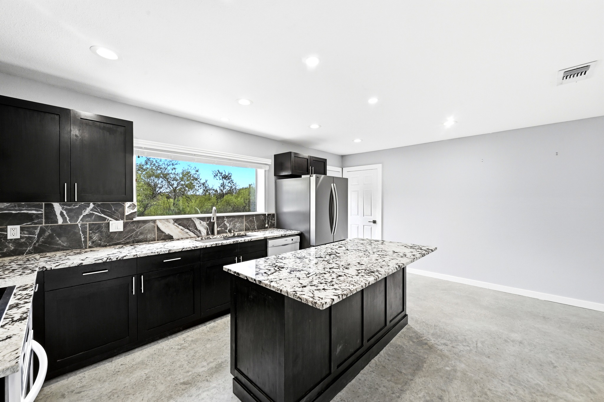 4001 Barth Road Lockhart, TX 78644 - Photo 13 of 38 Polished concrete floors and dark cabinetry define this modern kitchen with a central island.