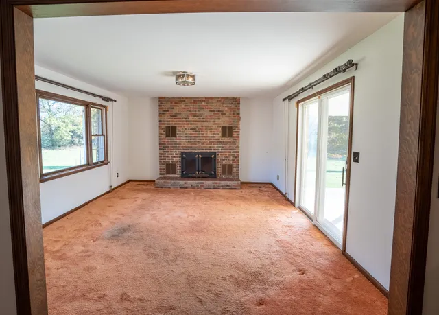 an empty room with windows and fireplace