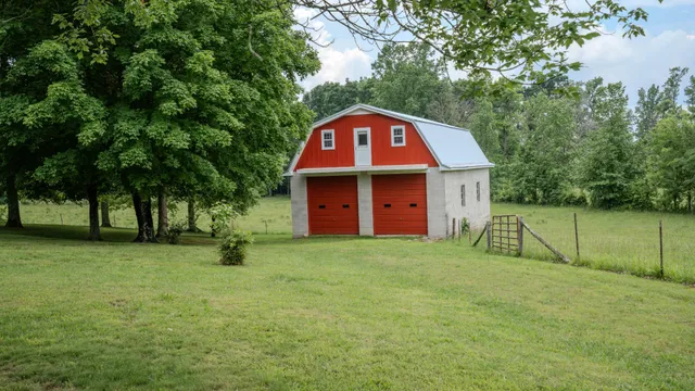 a view of a big house with a big yard and large trees