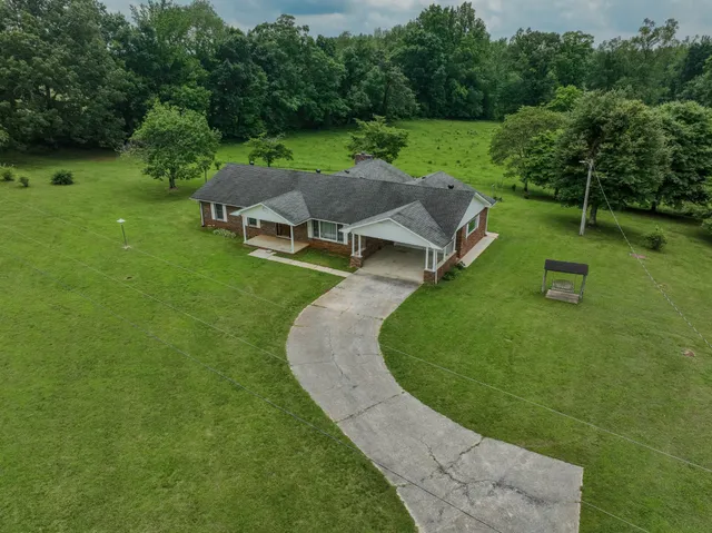 a view of house with yard and trees in the background