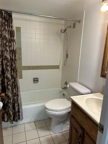 a bathroom with a granite countertop bathtub shower sink vanity and toilet