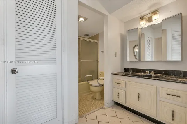 a spacious bathroom with a granite countertop toilet a sink and a mirror