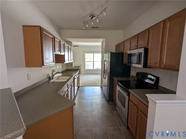 a kitchen with stainless steel appliances granite countertop a refrigerator a stove top oven a sink and dishwasher