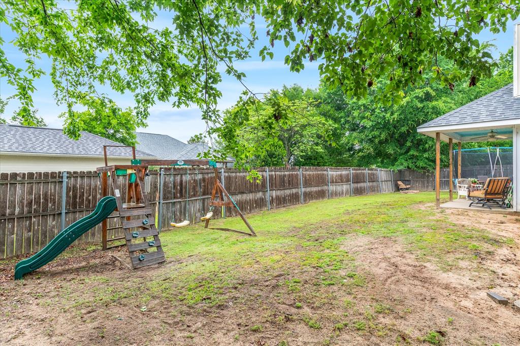 560 Washington Street Van, TX 75790 - Photo 28 of 29 a view of a backyard with a slide trees and wooden fence