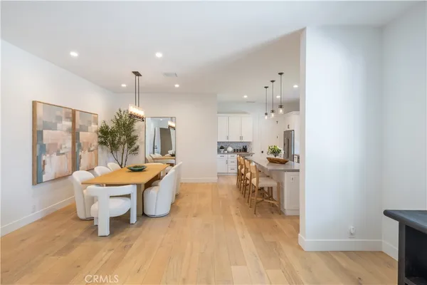 a kitchen with stainless steel appliances kitchen island granite countertop a stove a sink a refrigerator and white cabinets with wooden floor