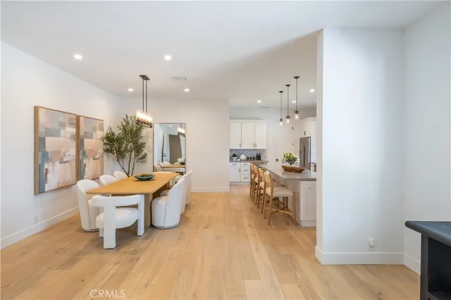 a kitchen with stainless steel appliances kitchen island granite countertop a stove a sink a refrigerator and white cabinets with wooden floor