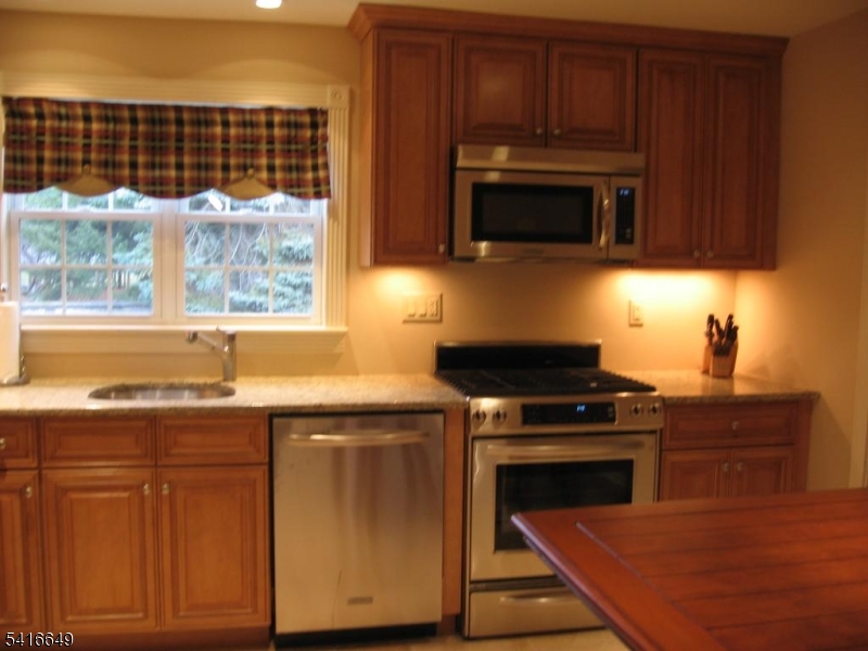 67 New England Avenue, Unit F Summit, NJ 07901 - Photo 7 of 16 a kitchen with stainless steel appliances wooden cabinets and a stove top oven