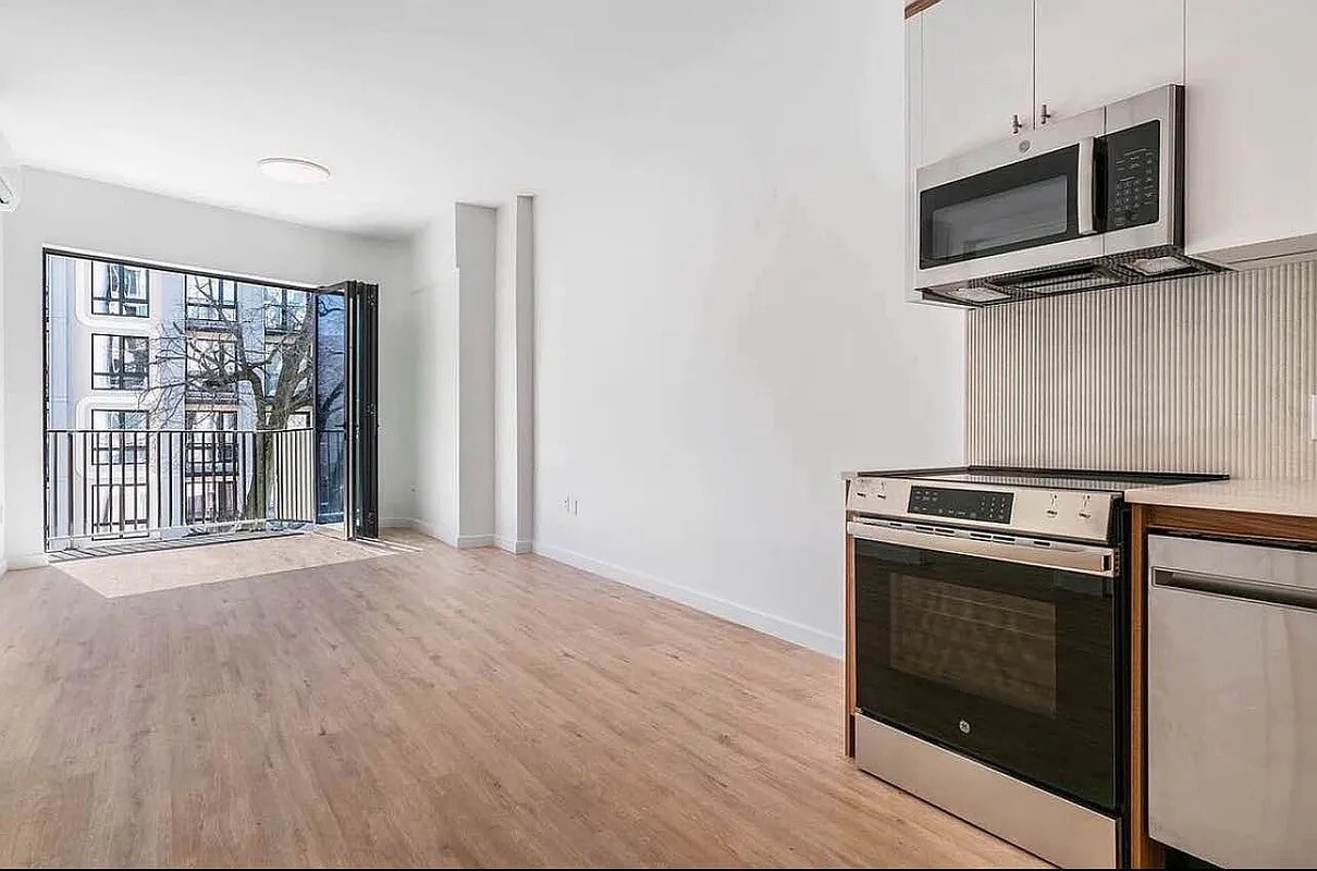 a living room with stainless steel appliances wooden floor and a window