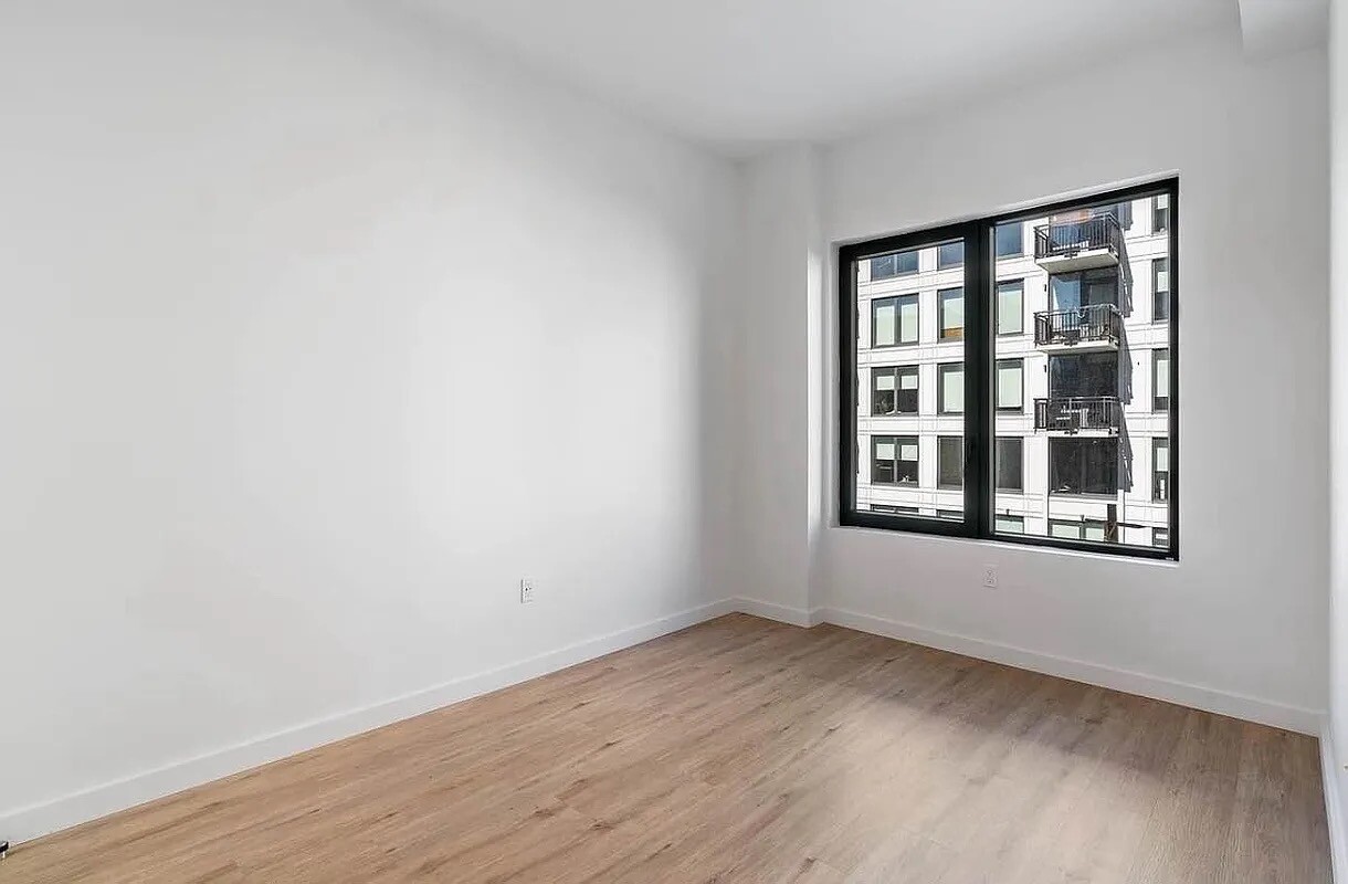 161 Lenox Road, Unit 512 Brooklyn, NY 11226 - Photo 5 of 13 wooden floor in an empty room with a window