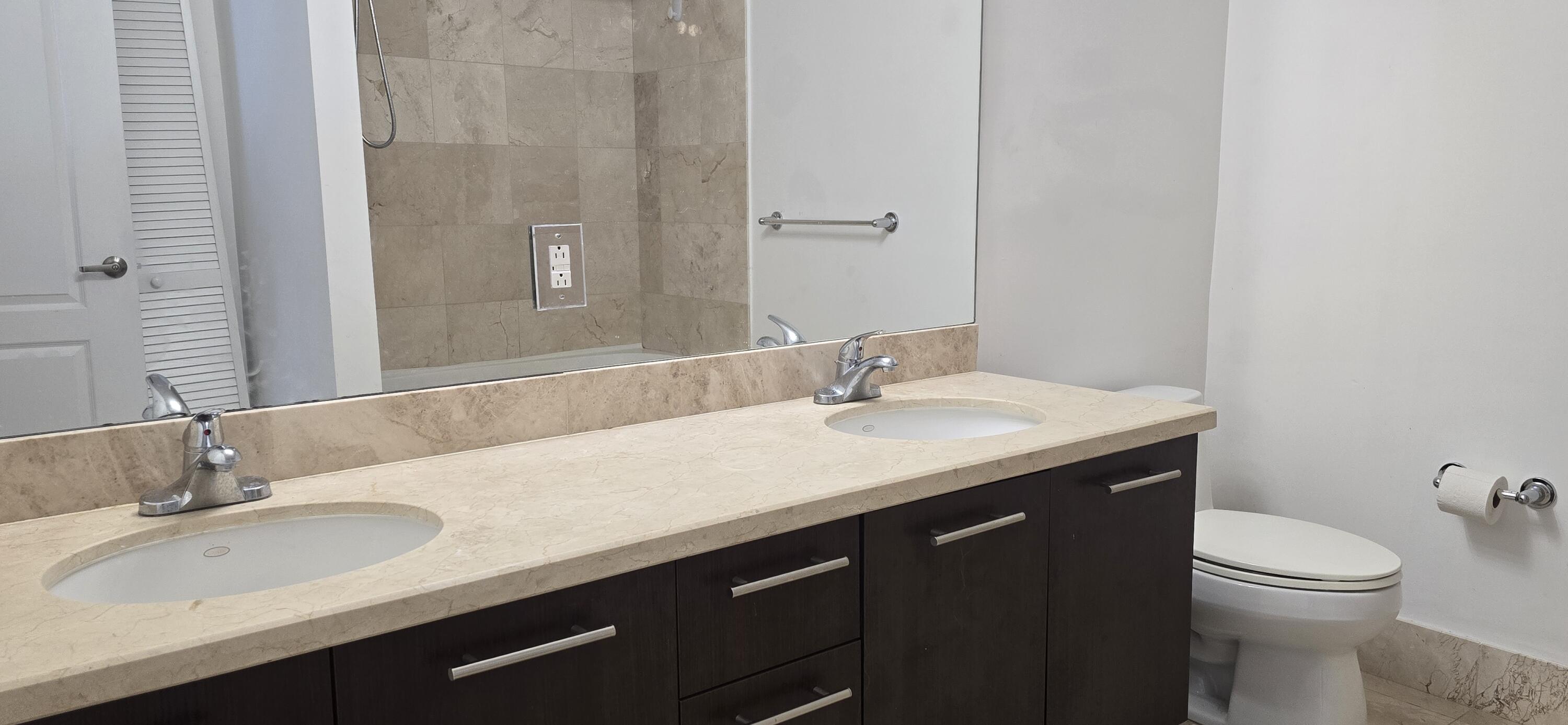 410 Evernia Street, Unit 616 West Palm Beach, FL 33401 - Photo 8 of 23 a bathroom with a granite countertop sink a toilet and a large mirror