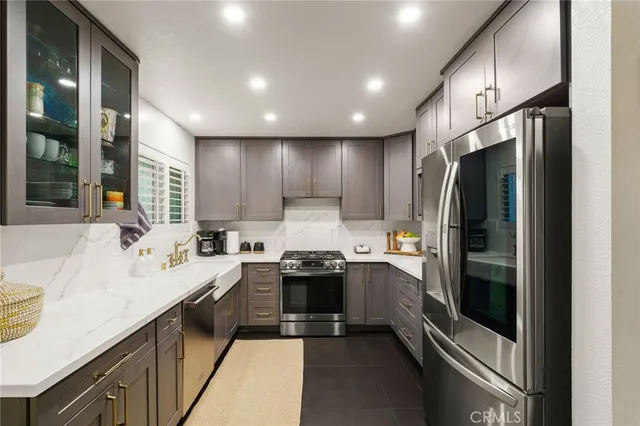 a kitchen with stainless steel appliances granite countertop a refrigerator a stove and a sink