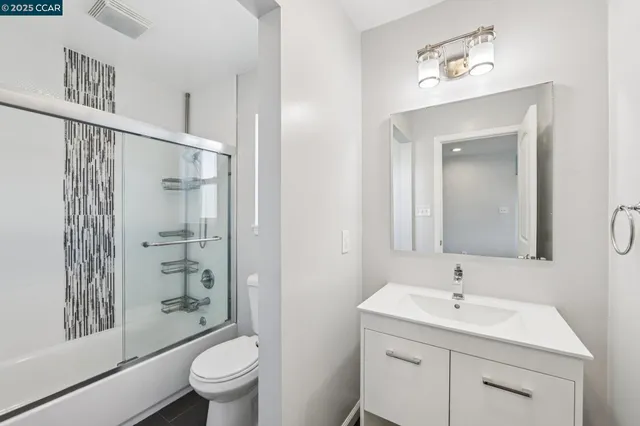 a bathroom with a toilet a sink a mirror a shower and vanity
