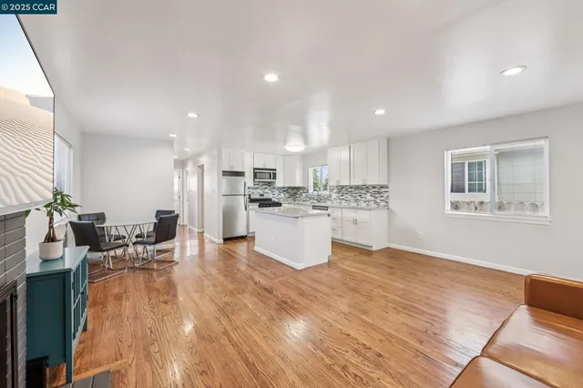 a living room with stainless steel appliances kitchen island wooden floors and living room view