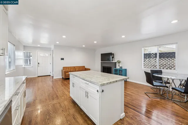a large white kitchen with wooden floor and a large window