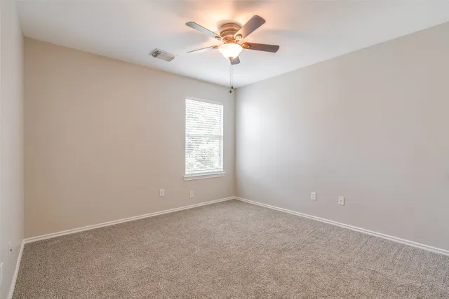 an empty room with windows and chandelier fan