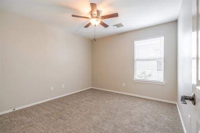an empty room with windows and fan