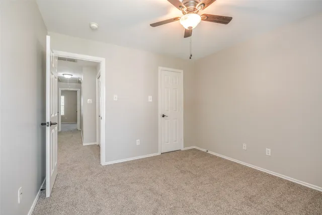an empty room with a chandelier fan and closet