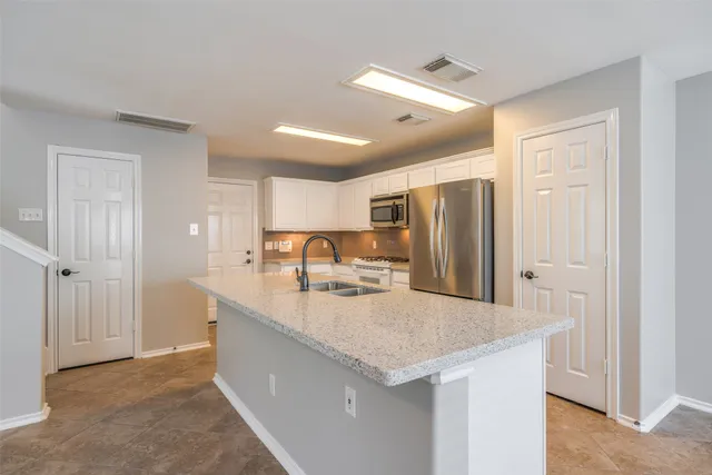 a kitchen with stainless steel appliances granite countertop a sink and a refrigerator