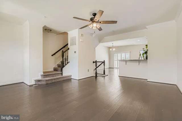 a view of an empty room with wooden floor and a ceiling fan