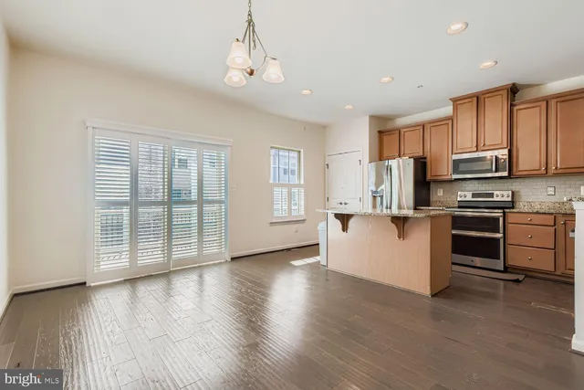 a kitchen with stainless steel appliances granite countertop a stove top oven a sink dishwasher a microwave oven and a refrigerator with wooden floor