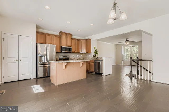 a kitchen with stainless steel appliances granite countertop a refrigerator a stove top oven a sink dishwasher a dining table and chairs with wooden floor