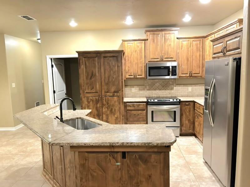 1118 Elk Ridge Drive Stephenville, TX 76401 - Photo 34 of 40 a kitchen with stainless steel appliances granite countertop a sink a stove and a refrigerator