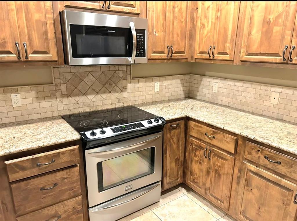 1118 Elk Ridge Drive Stephenville, TX 76401 - Photo 40 of 40 a kitchen with granite countertop a stove and a microwave