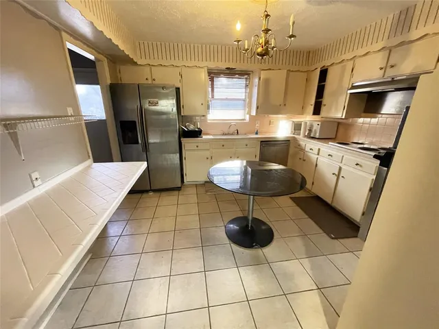 a kitchen with stainless steel appliances kitchen island granite countertop a sink refrigerator and cabinets