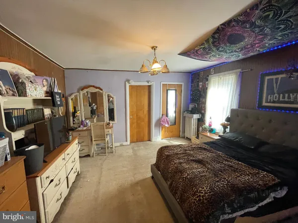 a spacious bedroom with a bed a mirror on dresser and a large window