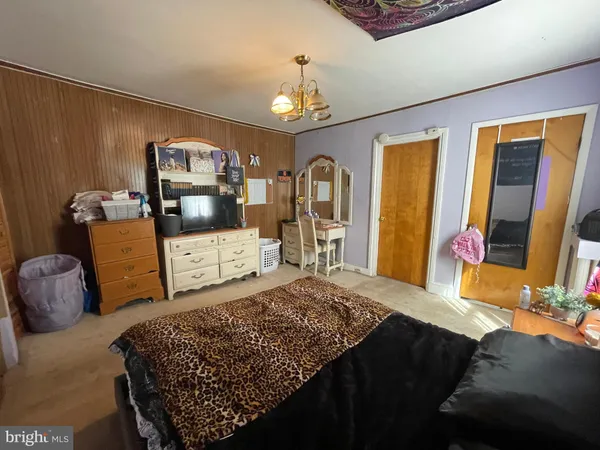 a bedroom with a bed a dresser and flat screen tv