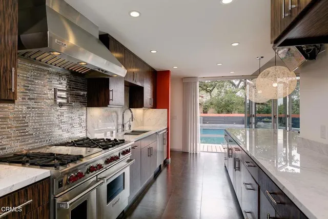 a kitchen with stainless steel appliances granite countertop a stove and a view of living room