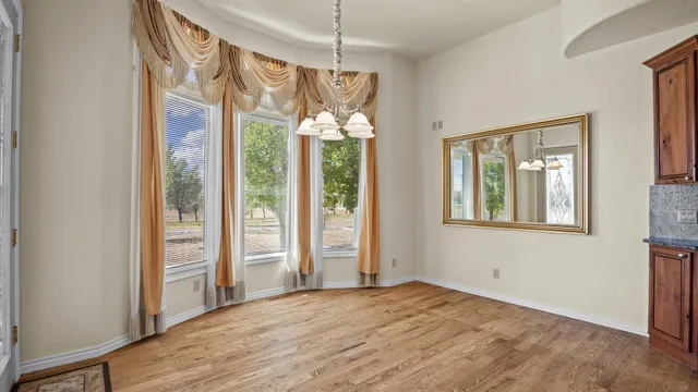 a view of an empty room with a window and chandelier fan