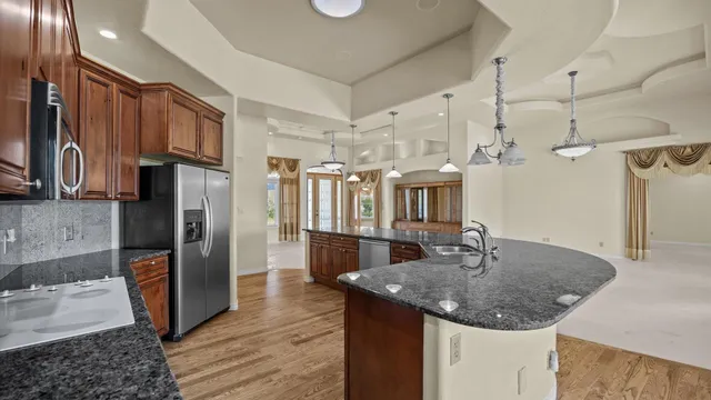 a kitchen with stainless steel appliances granite countertop a sink refrigerator and cabinets
