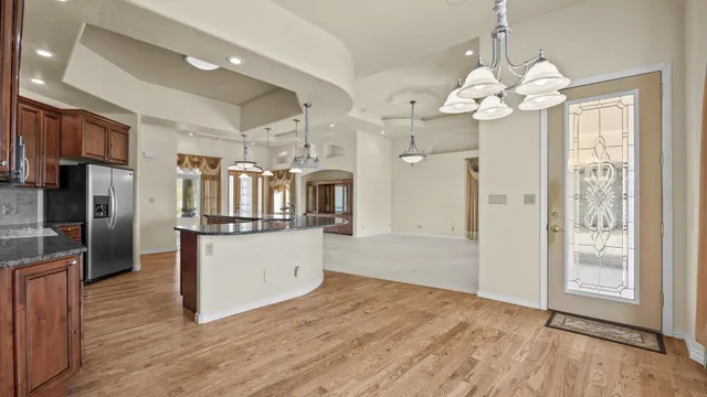 a kitchen with stainless steel appliances granite countertop a refrigerator a sink dishwasher a oven and a dining table with wooden floor