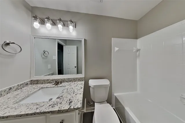 a bathroom with a granite countertop sink and a toilet