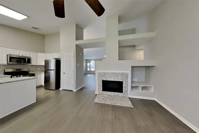 a living room with stainless steel appliances furniture a fireplace and wooden floor