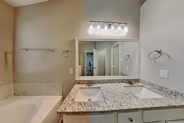 a bathroom with a granite countertop sink and a large mirror