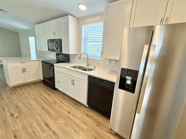 a kitchen with a sink a refrigerator a stove a microwave and white cabinets