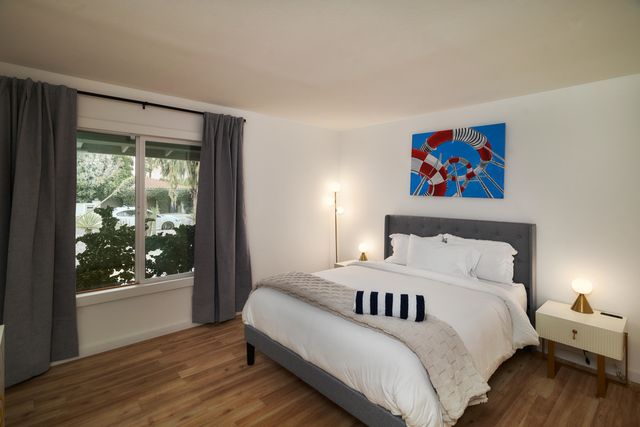 a bedroom with a bed painting on wall and a large window