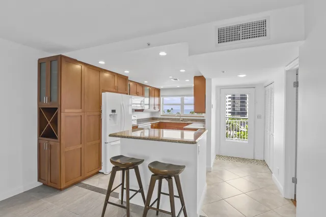 a kitchen with kitchen island wooden cabinets and refrigerator