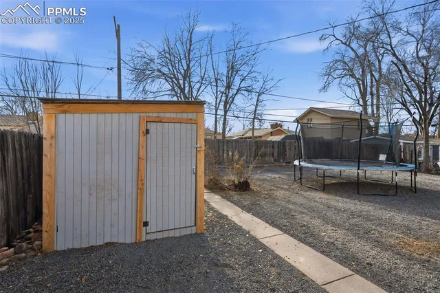 a backyard of a house with a bench and trees
