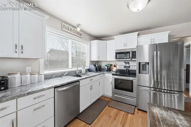 a kitchen with granite countertop a sink stainless steel appliances and cabinets