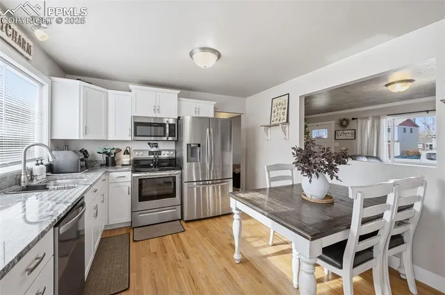 a kitchen with granite countertop stainless steel appliances a sink a stove a refrigerator cabinets and dining table