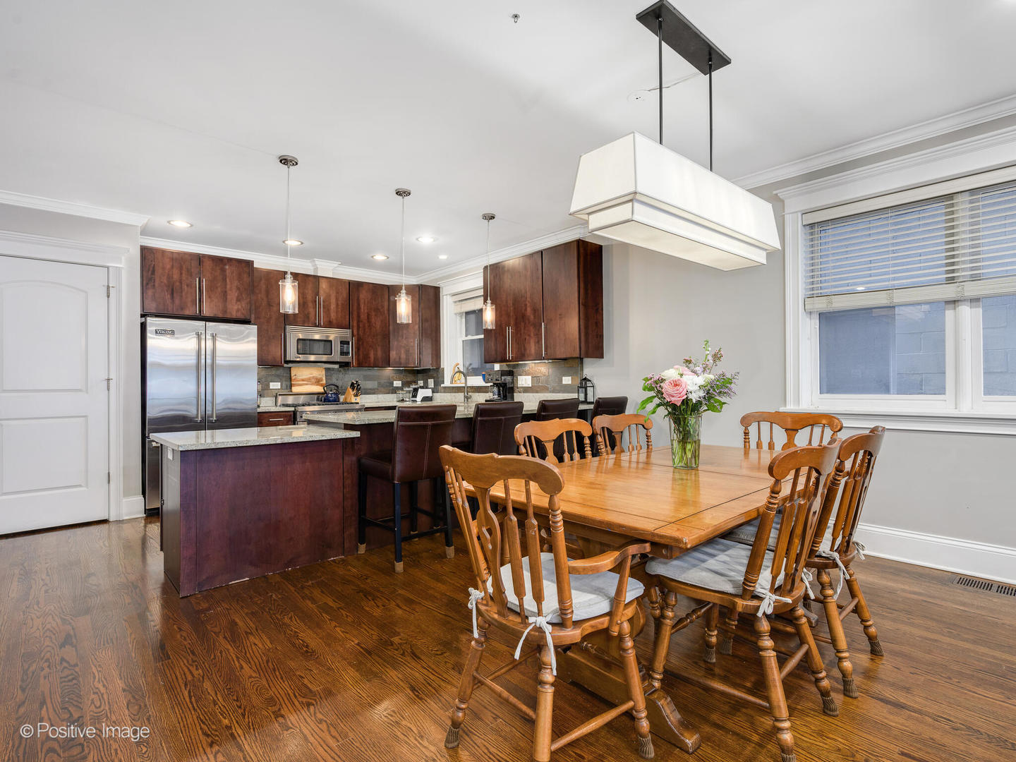 1745 West Roscoe Street, Unit 1 Chicago, IL 60657 - Photo 5 of 29 a kitchen with stainless steel appliances a dining table chairs refrigerator and microwave