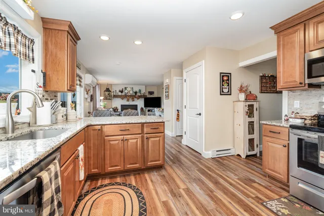 a kitchen with stainless steel appliances granite countertop a refrigerator a stove and a sink with wooden floors