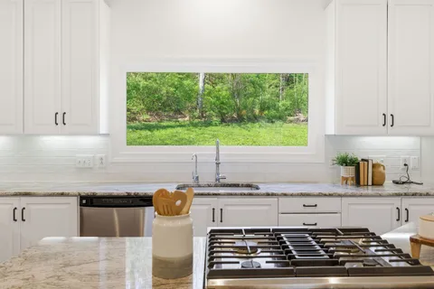 a kitchen with granite countertop a stove and a white wooden cabinets