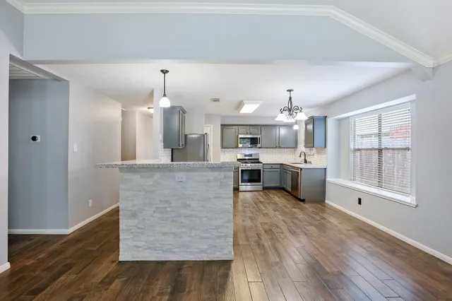 a large kitchen with kitchen island a stove a sink dishwasher and wooden floor