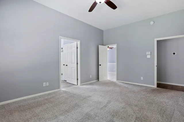 an empty room with ceiling fan and window