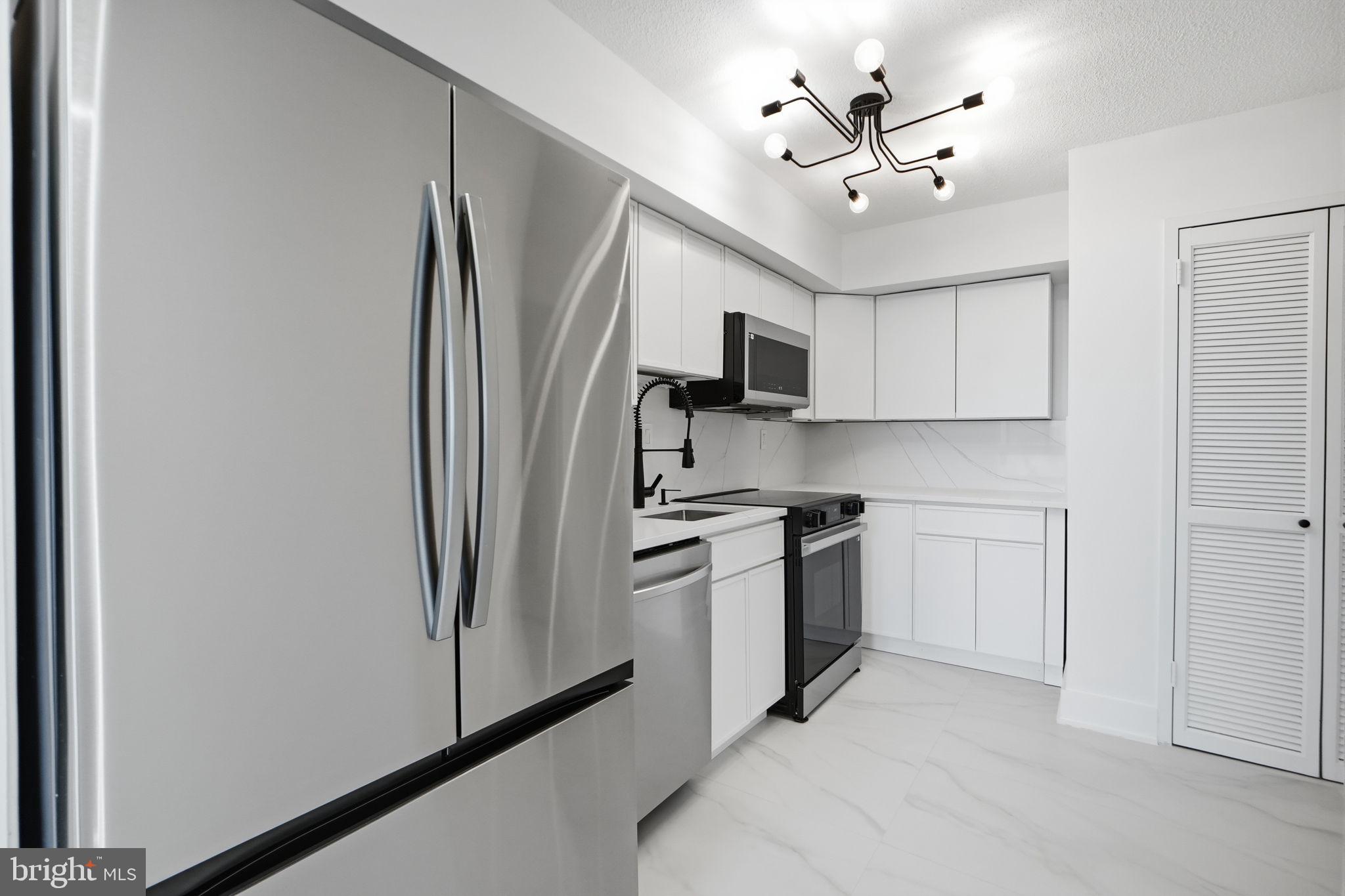 1808 Old Meadow Road, Unit 1201 McLean, VA 22102 - Photo 13 of 37 a kitchen with stainless steel appliances granite countertop a refrigerator a stove a sink a oven with white cabinets and a refrigerator