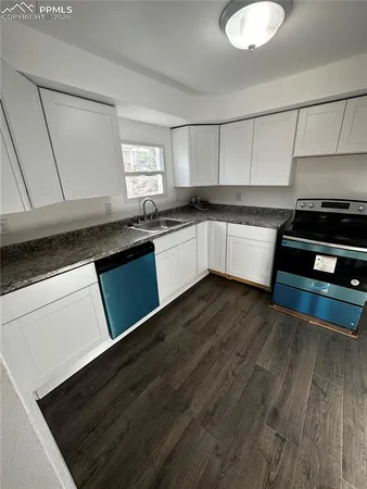 a kitchen with granite countertop wooden cabinets a stove and a sink